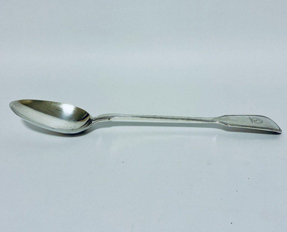 A Victorian silver serving spoon displaying a fiddle pattern handle with an engraved crest on the terminal. View II