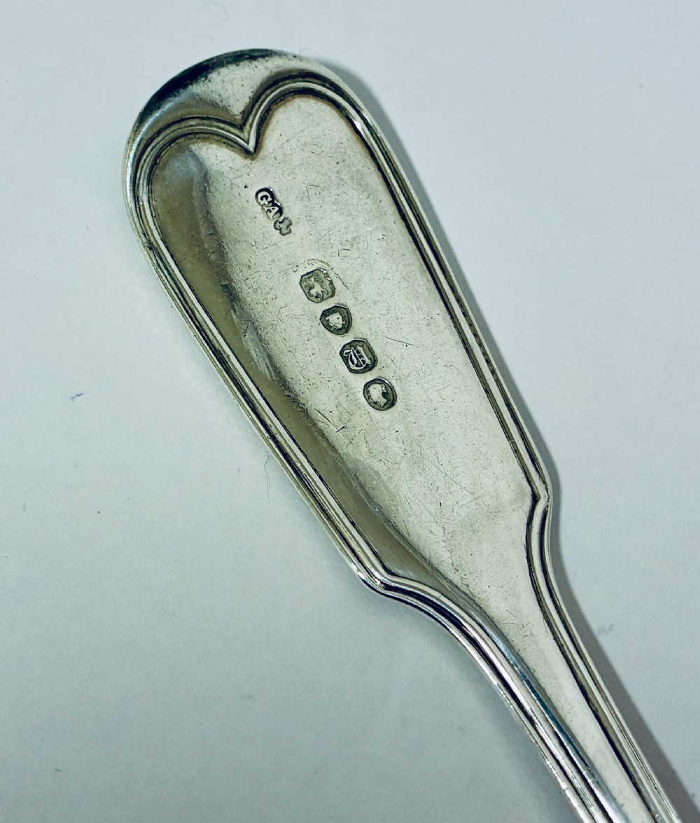 A Victorian silver serving spoon displaying a fiddle pattern handle with an engraved crest on the terminal. View VIII
