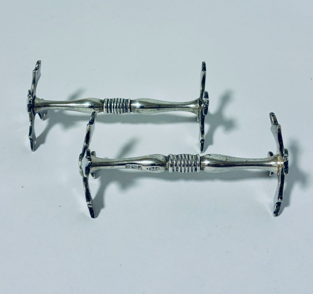 A pair of antique sterling silver knife rests with ribbed central bars and star-shaped pierced ends.