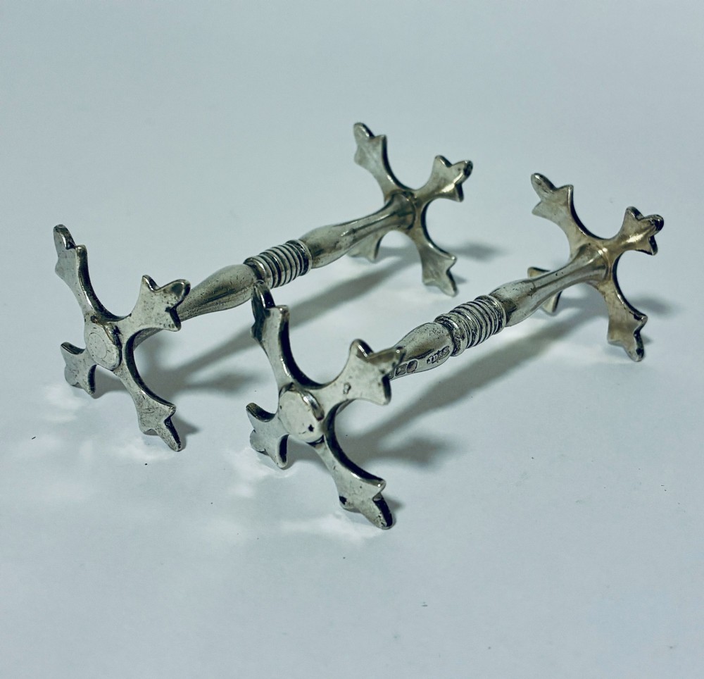 A pair of antique sterling silver knife rests with ribbed central bars and star-shaped pierced ends. View II