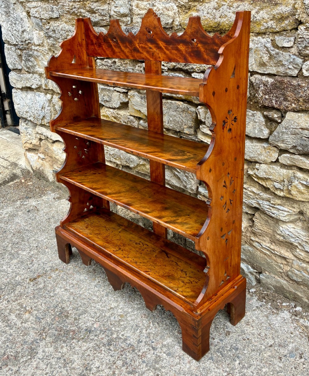 An Arts and Crafts satinwood open bookcase featuring four tiered shelves with a scalloped top gallery, shaped sides, and decorative pierced cut-outs. View II