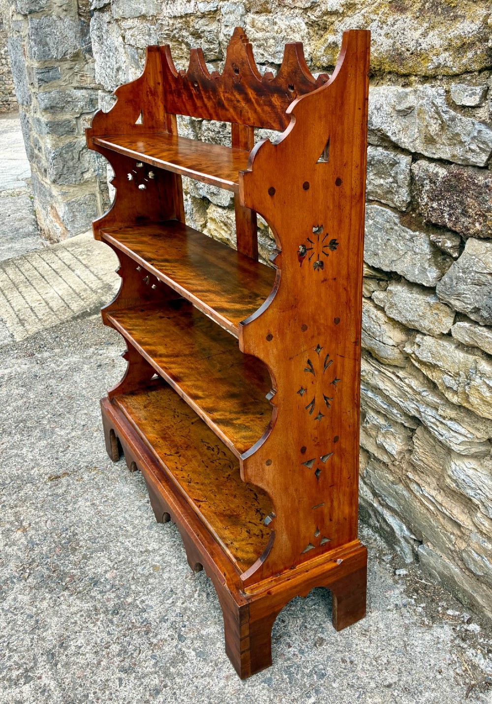An Arts and Crafts satinwood open bookcase featuring four tiered shelves with a scalloped top gallery, shaped sides, and decorative pierced cut-outs. View III