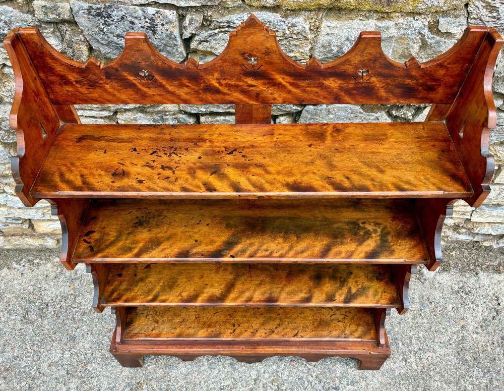 An Arts and Crafts satinwood open bookcase featuring four tiered shelves with a scalloped top gallery, shaped sides, and decorative pierced cut-outs. View V