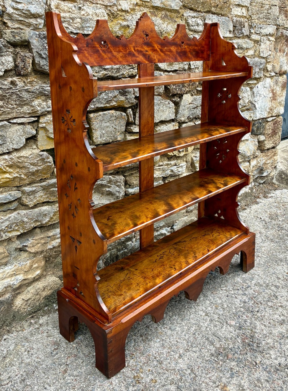 An Arts and Crafts satinwood open bookcase featuring four tiered shelves with a scalloped top gallery, shaped sides, and decorative pierced cut-outs. View VI