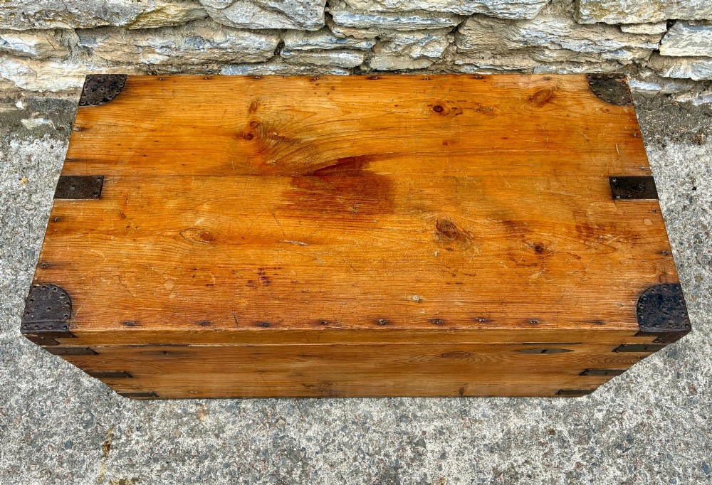 An antique rectangular pine campaign trunk with dark metal corner brackets, a brass escutcheon, and visible natural wood grain. View II