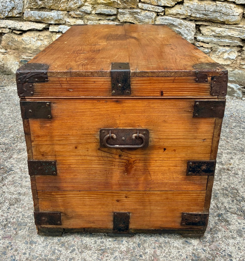 An antique rectangular pine campaign trunk with dark metal corner brackets, a brass escutcheon, and visible natural wood grain. View IX