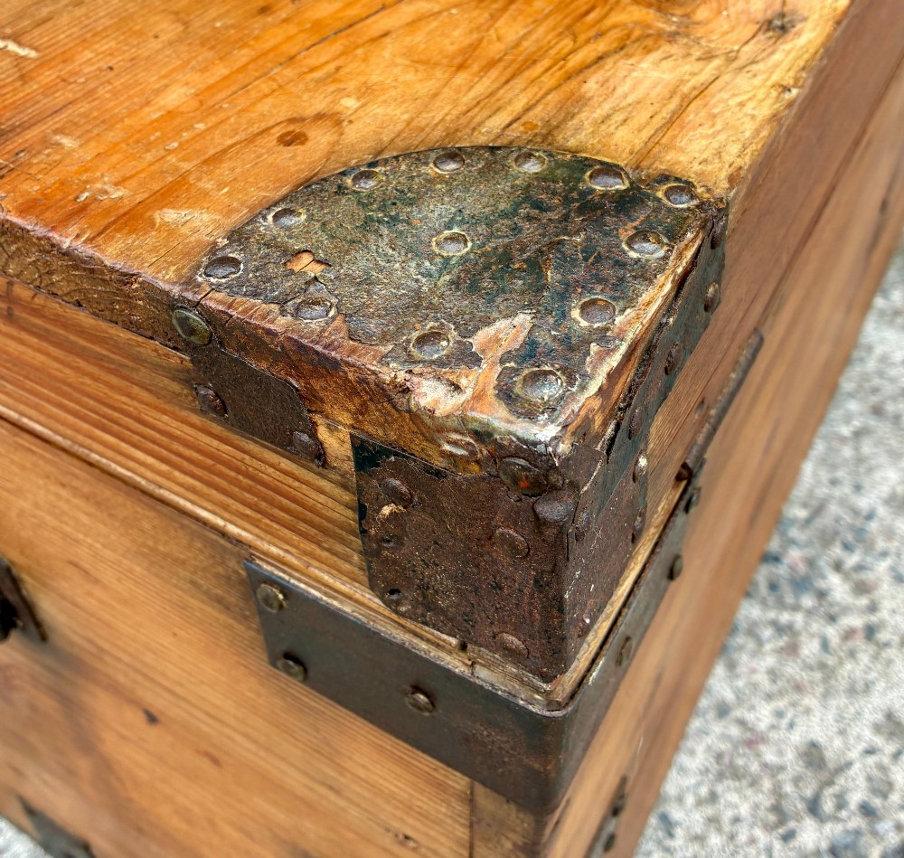 An antique rectangular pine campaign trunk with dark metal corner brackets, a brass escutcheon, and visible natural wood grain. View XI