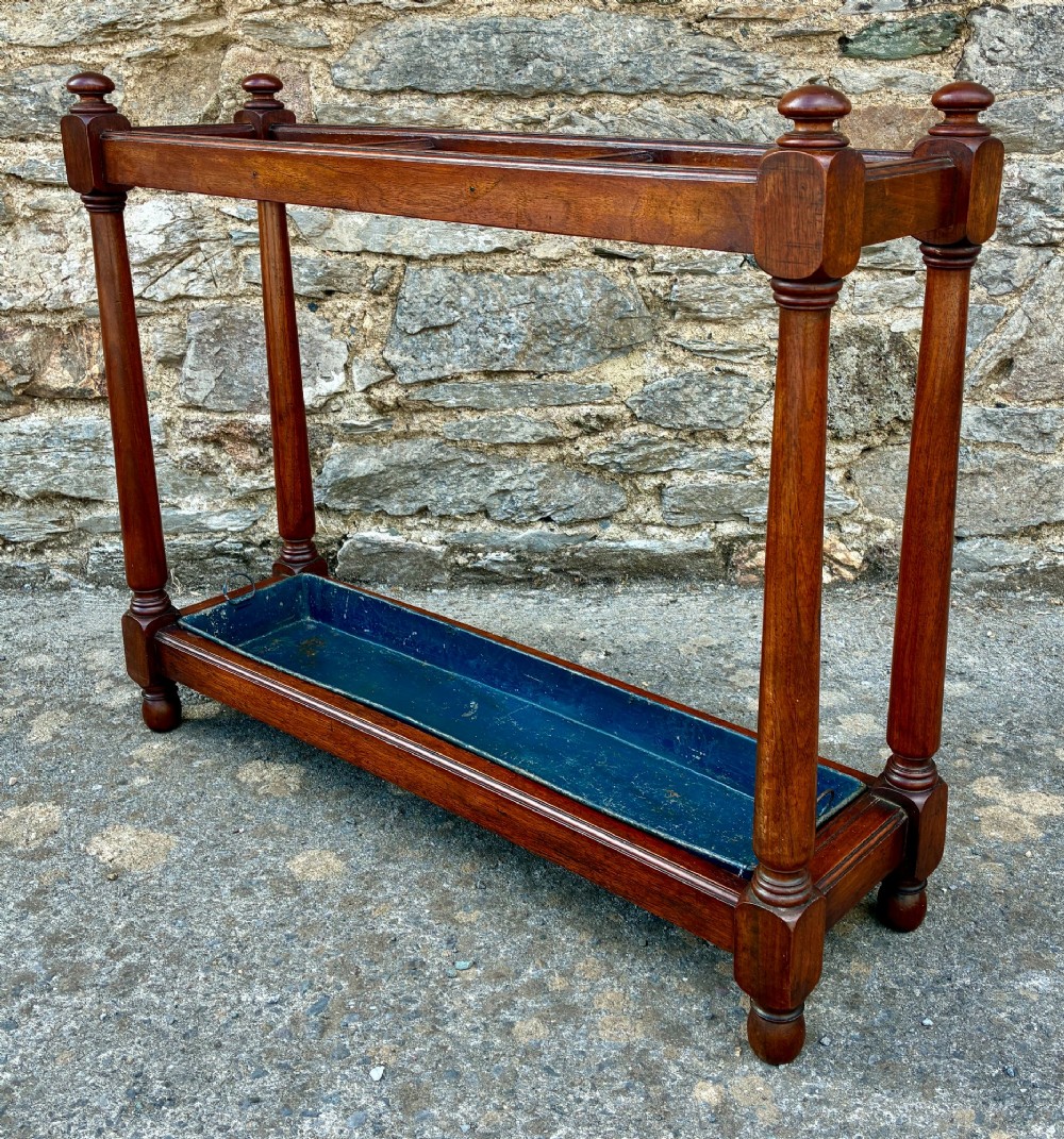 A Victorian mahogany umbrella stand with four divided top sections, turned support legs with ball finials, and a removable blue painted metal drip tray. View III