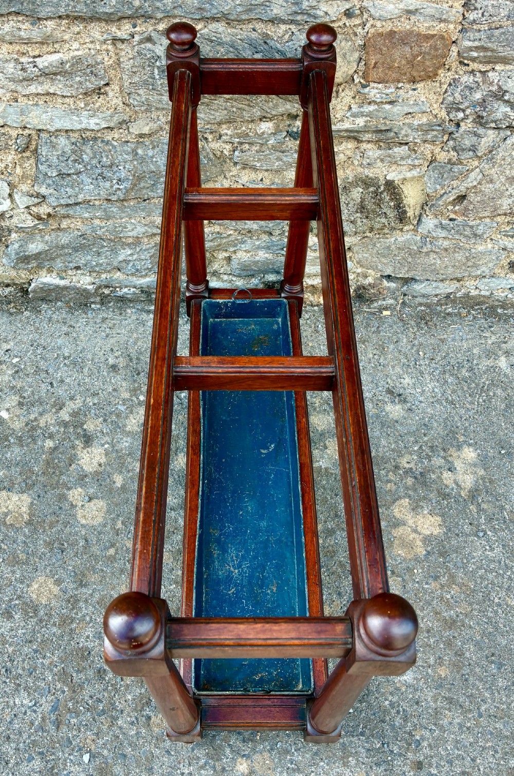 A Victorian mahogany umbrella stand with four divided top sections, turned support legs with ball finials, and a removable blue painted metal drip tray. View V