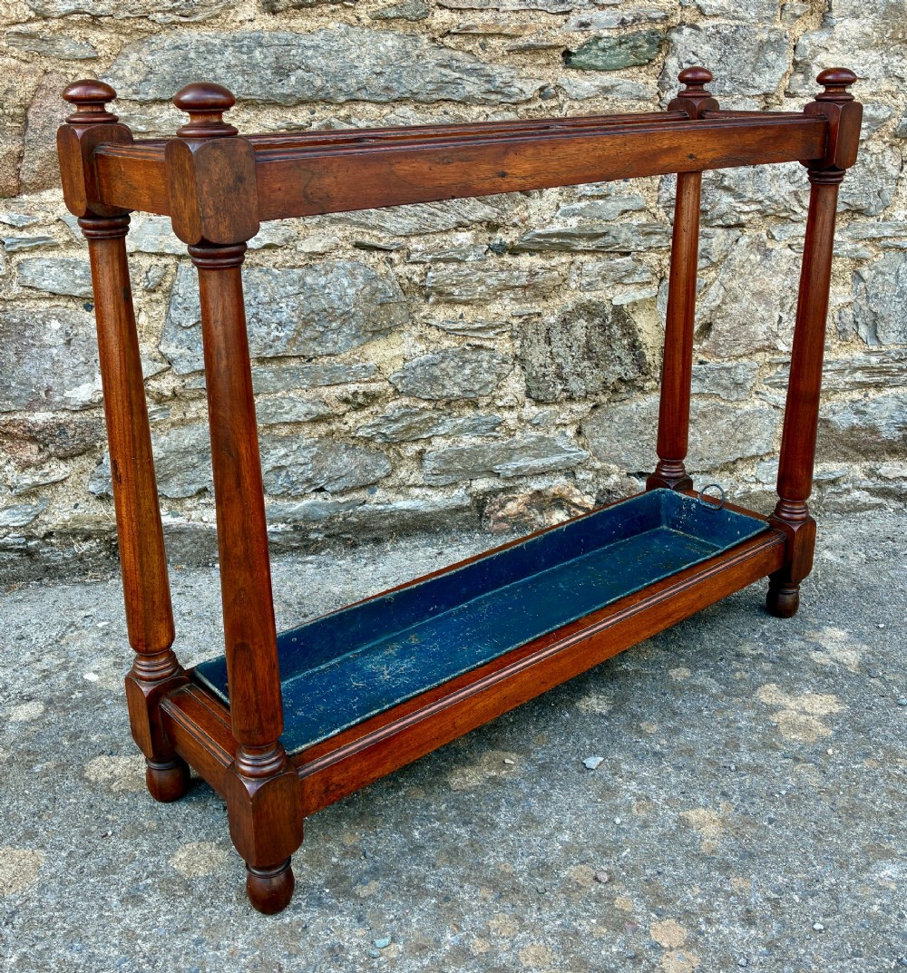 A Victorian mahogany umbrella stand with four divided top sections, turned support legs with ball finials, and a removable blue painted metal drip tray. View VI