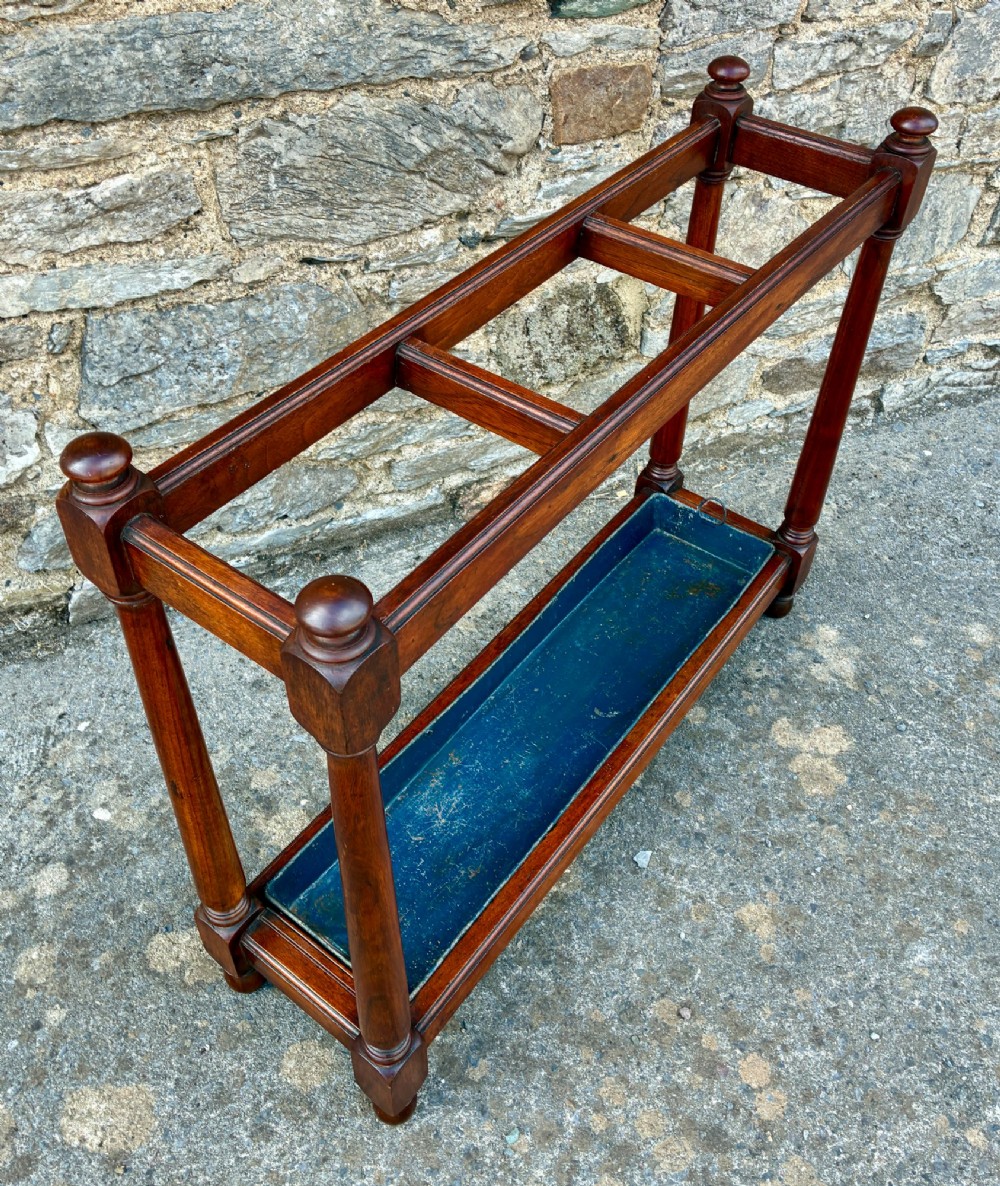 A Victorian mahogany umbrella stand with four divided top sections, turned support legs with ball finials, and a removable blue painted metal drip tray. View VII