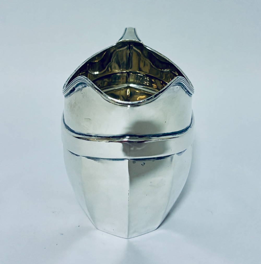 An antique polished silver milk jug featuring a faceted lower body, a shaped pouring spout with reeded rim, and an angular handle. View III