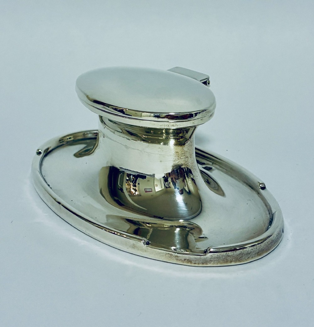 A solid silver capstan-shaped inkwell with a broad flared circular base and a hinged domed lid. View III