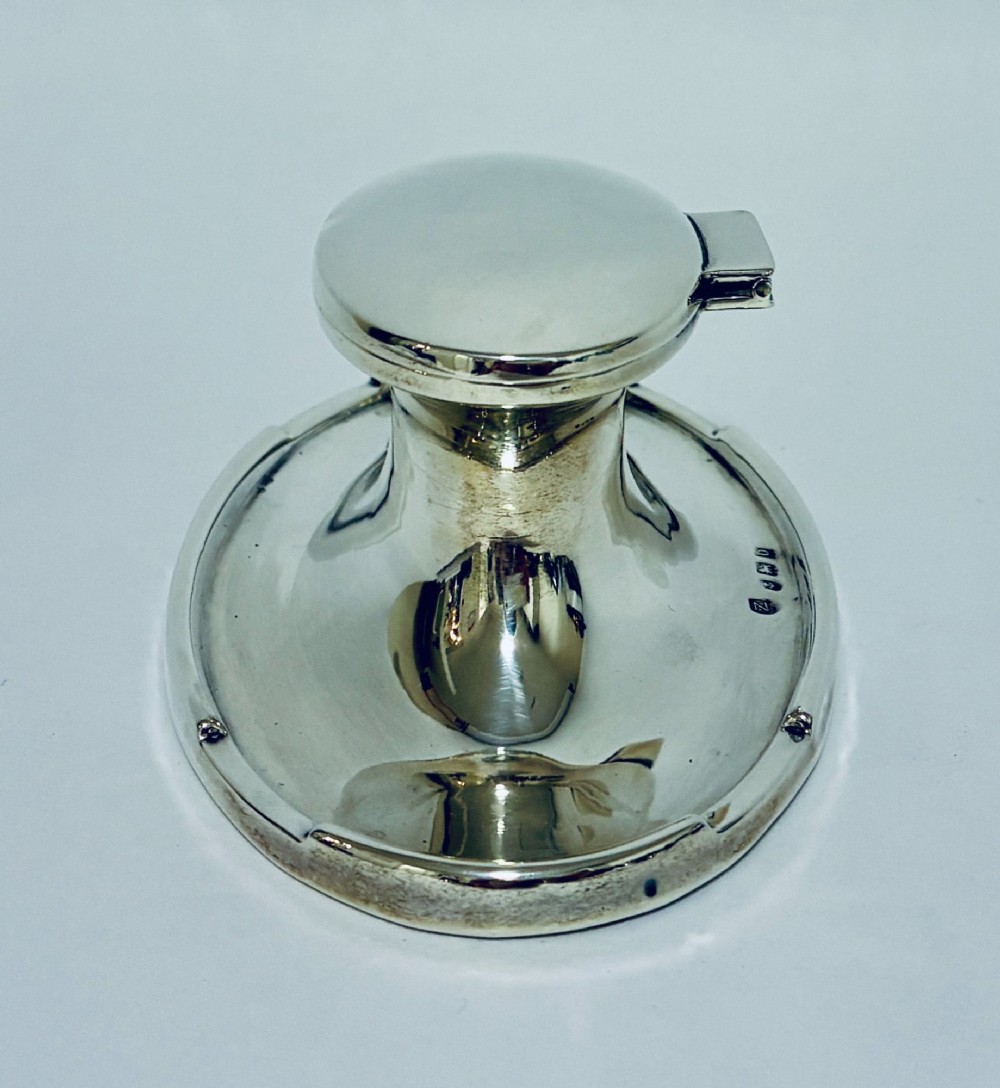 A solid silver capstan-shaped inkwell with a broad flared circular base and a hinged domed lid. View IV