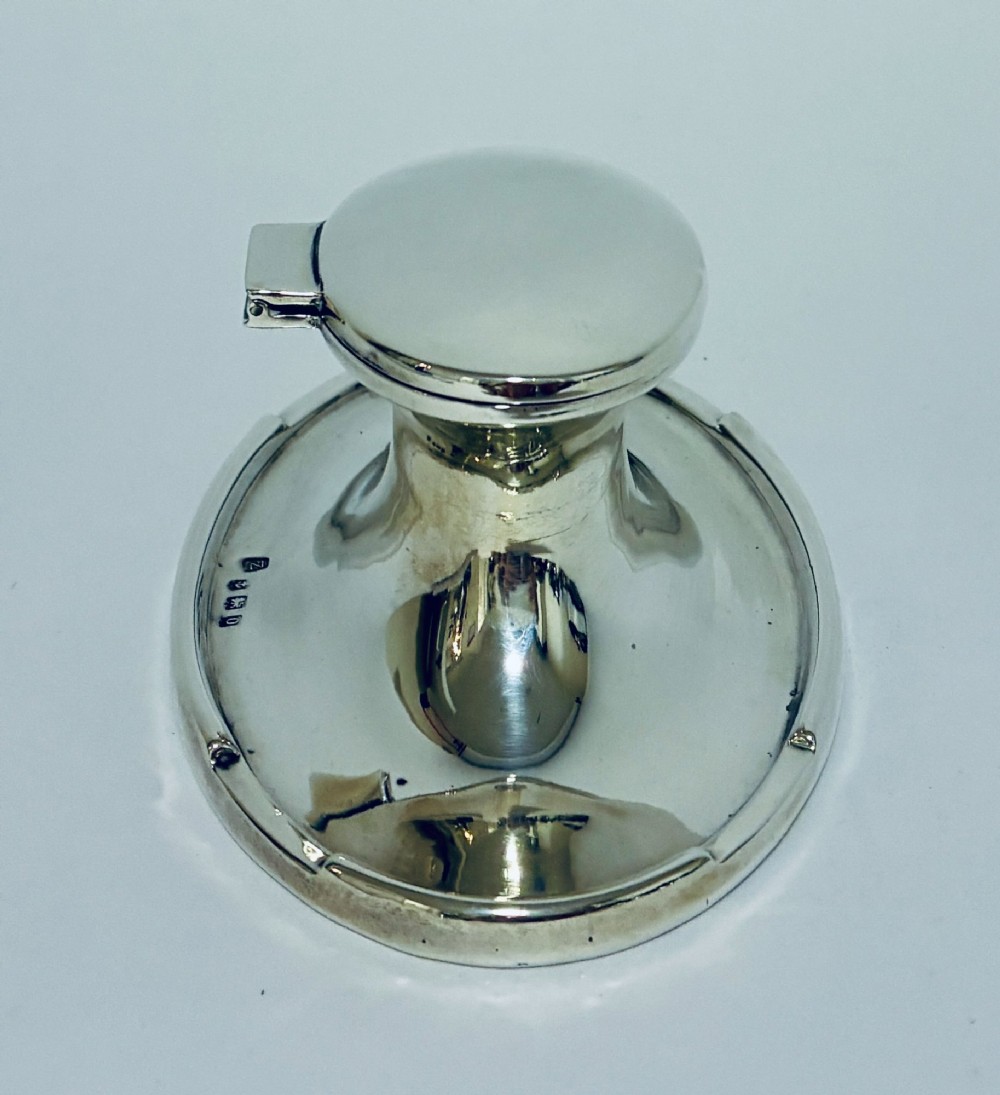 A solid silver capstan-shaped inkwell with a broad flared circular base and a hinged domed lid. View VI