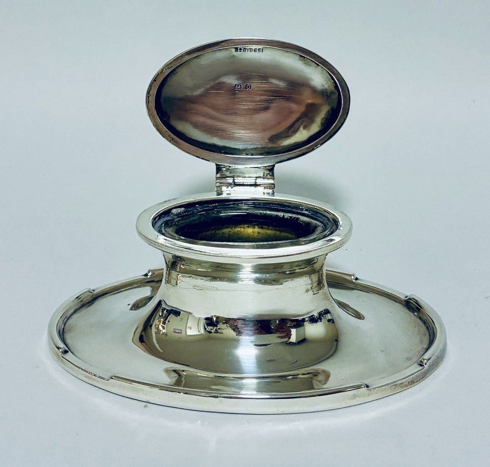 A solid silver capstan-shaped inkwell with a broad flared circular base and a hinged domed lid. View IX