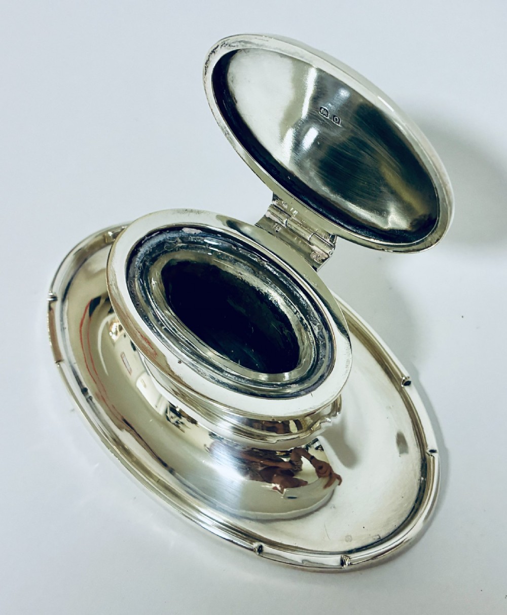 A solid silver capstan-shaped inkwell with a broad flared circular base and a hinged domed lid. View X