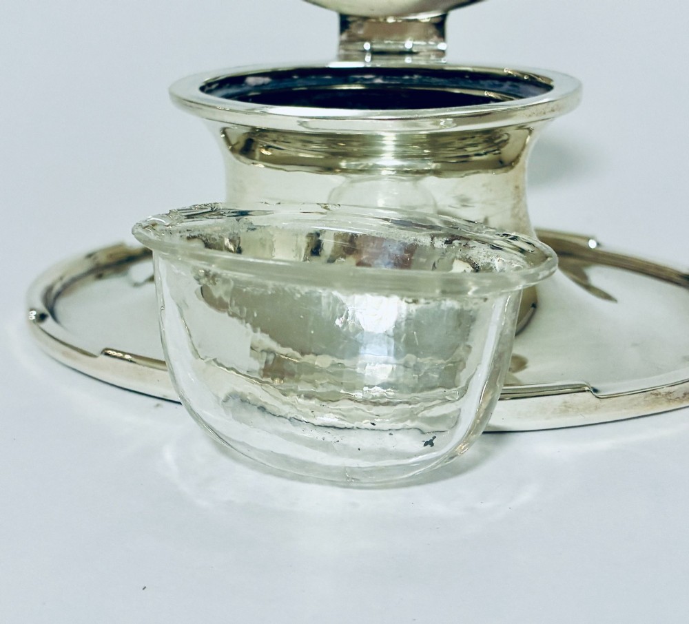 A solid silver capstan-shaped inkwell with a broad flared circular base and a hinged domed lid. View XI