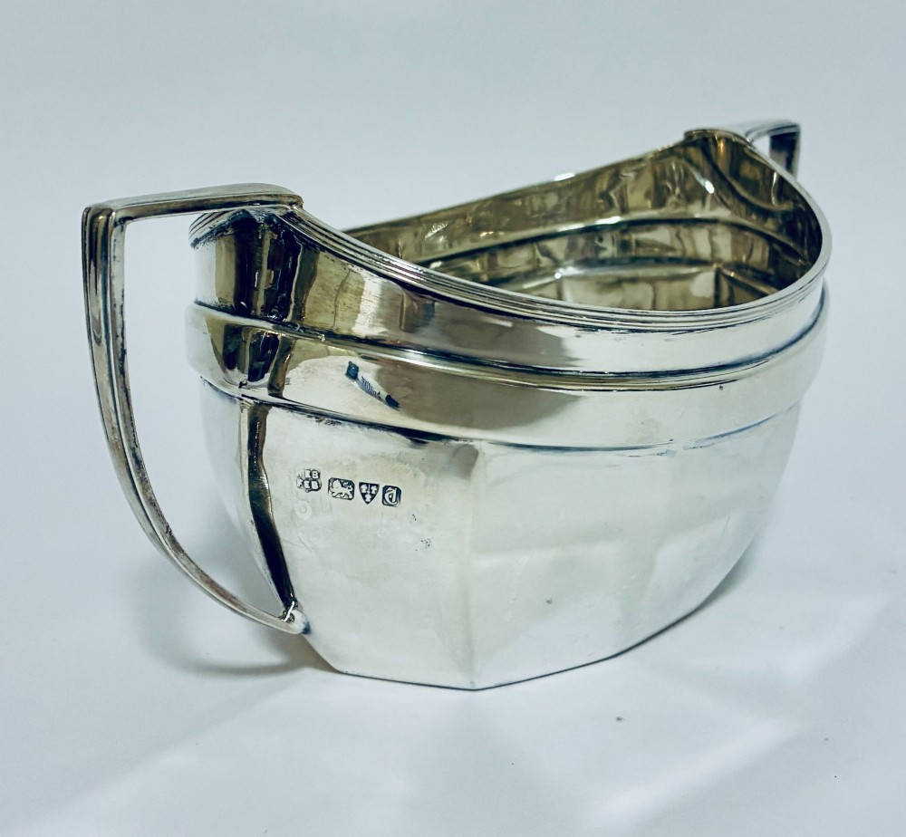 An antique silver twin-handled sugar bowl featuring angular handles, a faceted lower body, and visible hallmarks on the side. View II