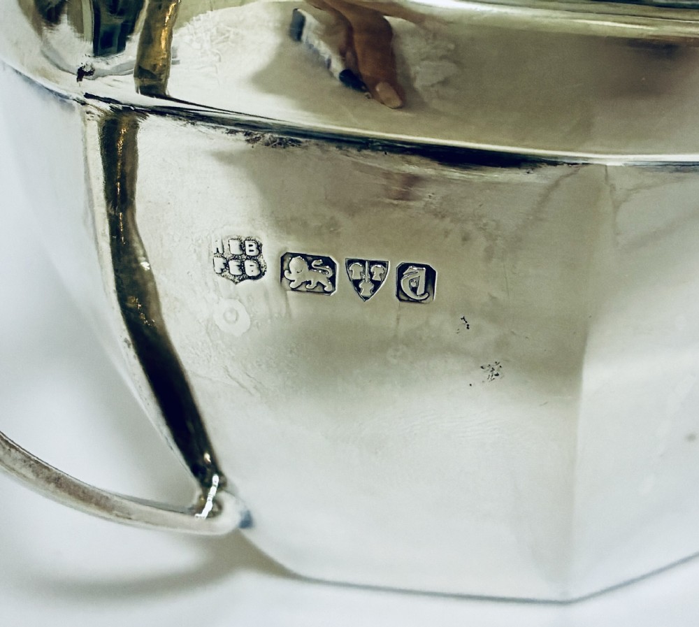 An antique silver twin-handled sugar bowl featuring angular handles, a faceted lower body, and visible hallmarks on the side. View III