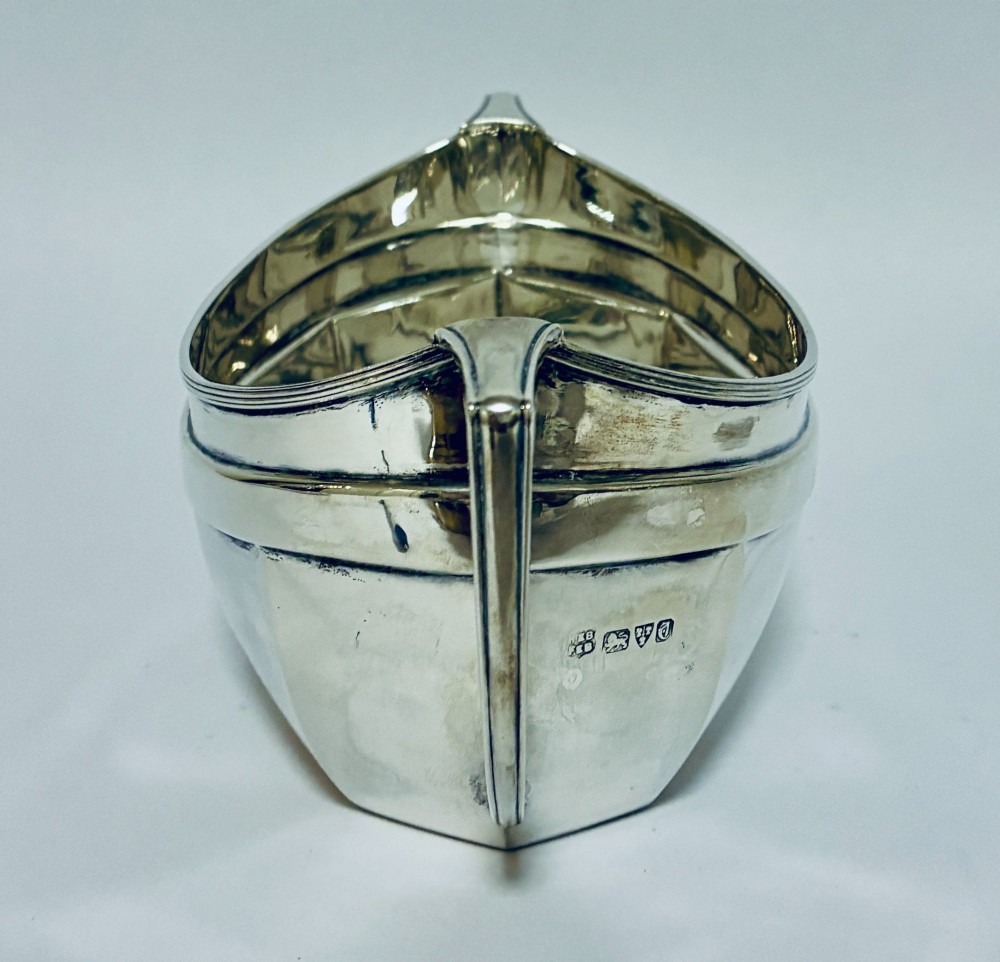 An antique silver twin-handled sugar bowl featuring angular handles, a faceted lower body, and visible hallmarks on the side. View IV