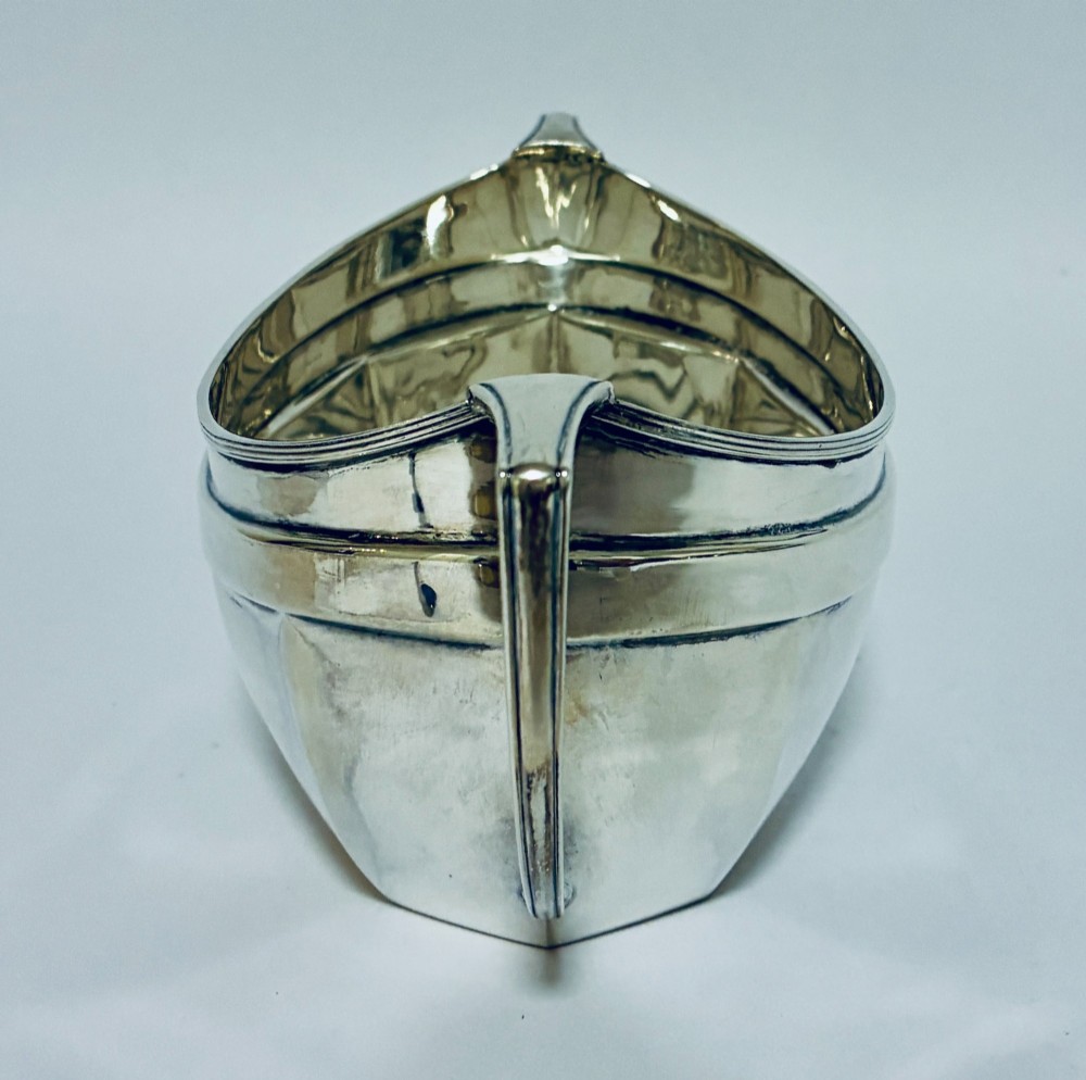 An antique silver twin-handled sugar bowl featuring angular handles, a faceted lower body, and visible hallmarks on the side. View VII
