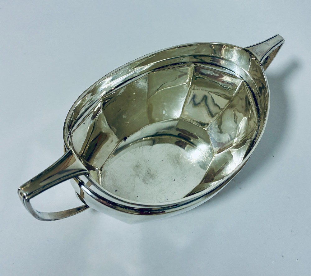 An antique silver twin-handled sugar bowl featuring angular handles, a faceted lower body, and visible hallmarks on the side. View VIII