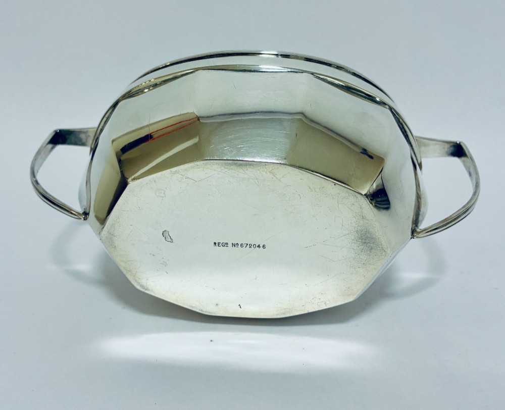 An antique silver twin-handled sugar bowl featuring angular handles, a faceted lower body, and visible hallmarks on the side. View IX