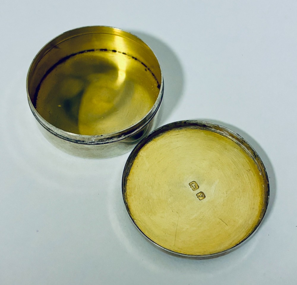 A round antique silver pill box featuring engine-turned geometric patterns on the lid. View V