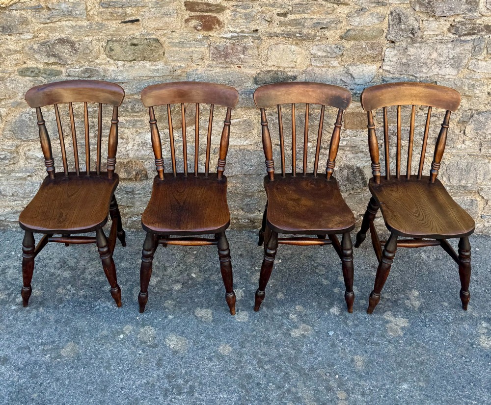 A set of four dark brown Victorian wooden kitchen chairs featuring spindle backs, shaped seats, and turned legs. View II