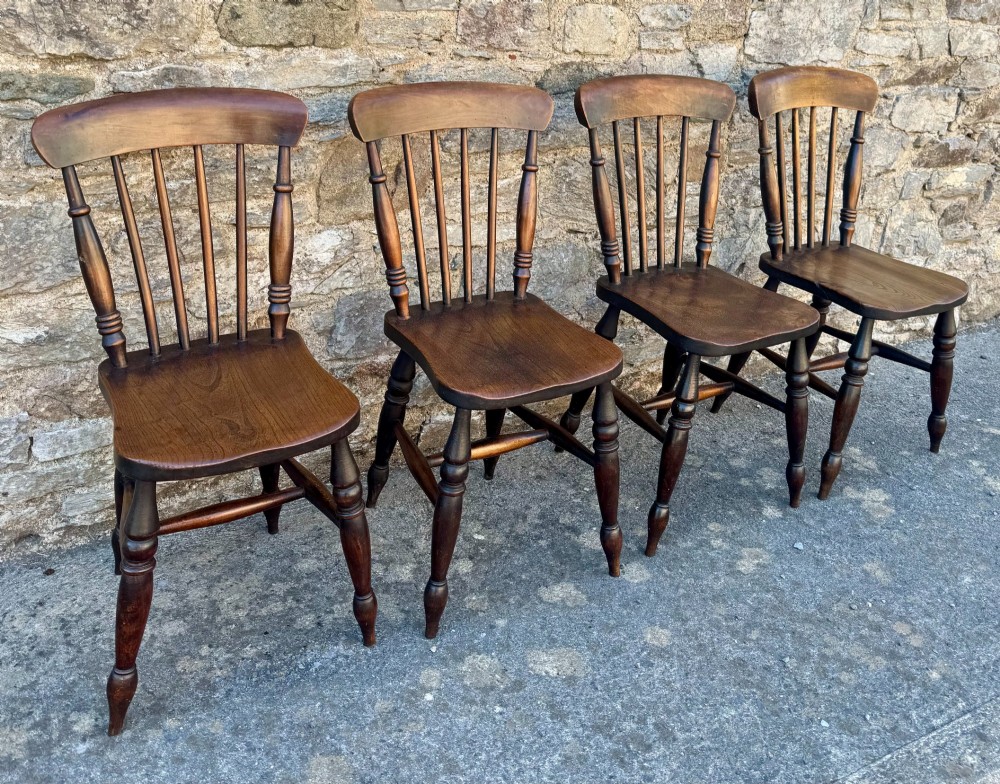 A set of four dark brown Victorian wooden kitchen chairs featuring spindle backs, shaped seats, and turned legs. View III