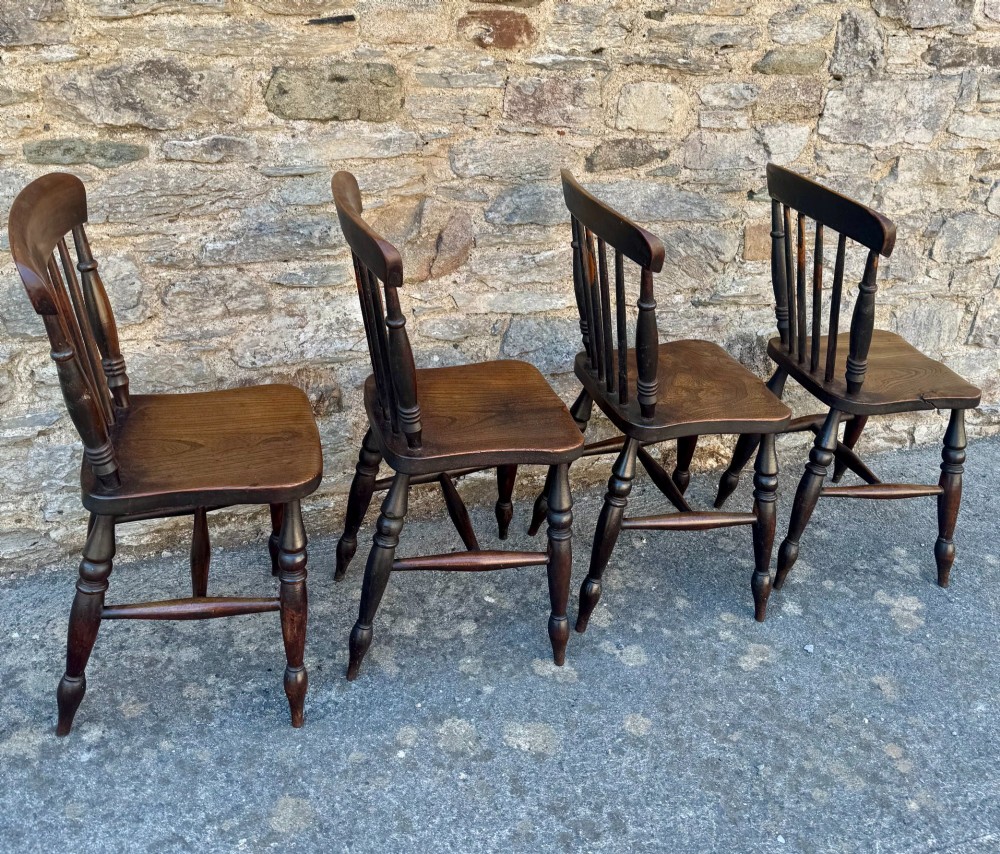 A set of four dark brown Victorian wooden kitchen chairs featuring spindle backs, shaped seats, and turned legs. View IV