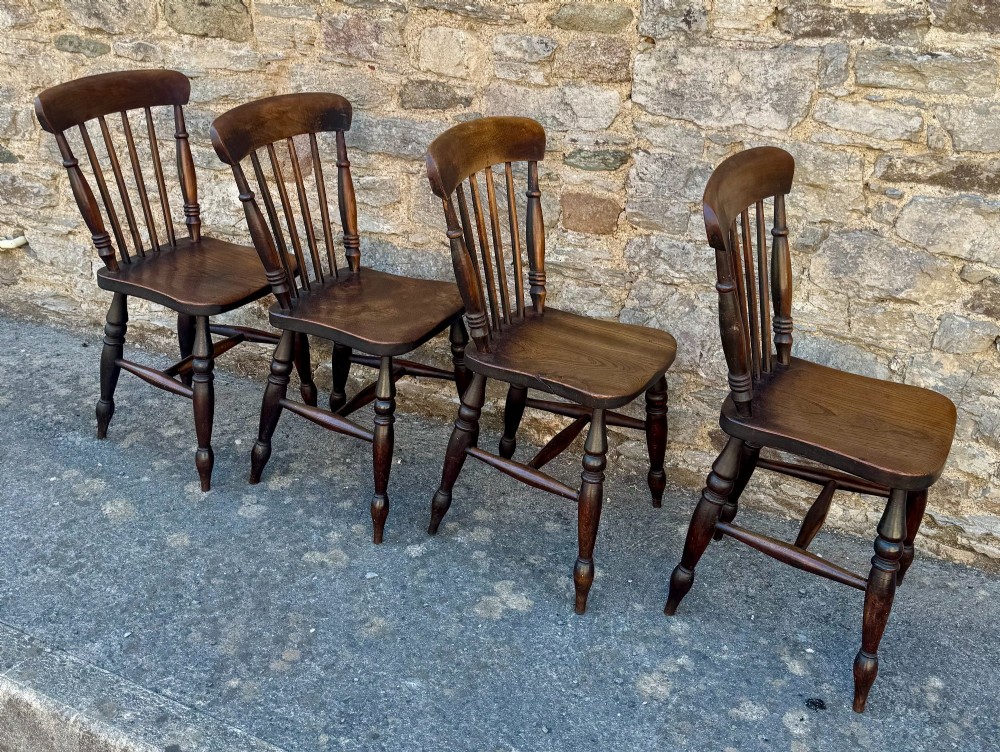 A set of four dark brown Victorian wooden kitchen chairs featuring spindle backs, shaped seats, and turned legs. View V