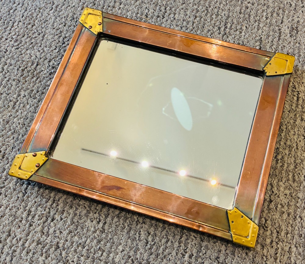A rectangular wall mirror featuring a sheet copper frame reinforced with riveted brass corner plates. View IV