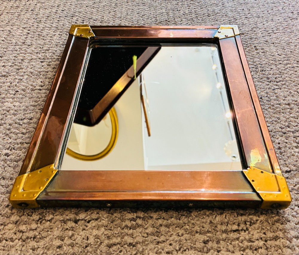 A rectangular wall mirror featuring a sheet copper frame reinforced with riveted brass corner plates. View V