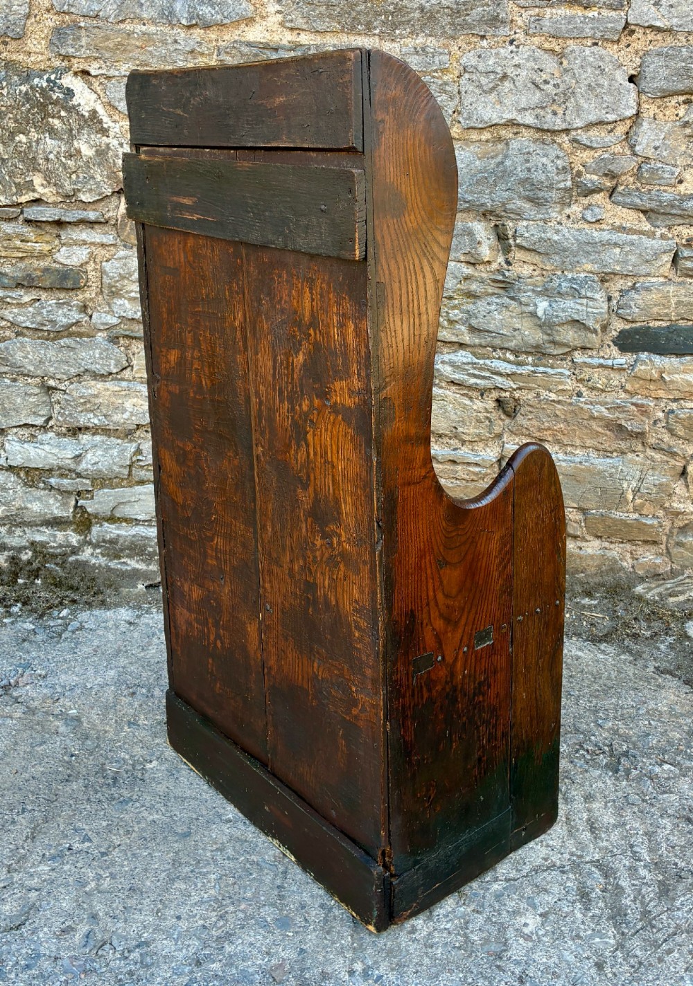 A dark oak primitive lambing chair featuring high winged sides, a tall two-panel back, a solid timber seat, and an enclosed box base. View IX