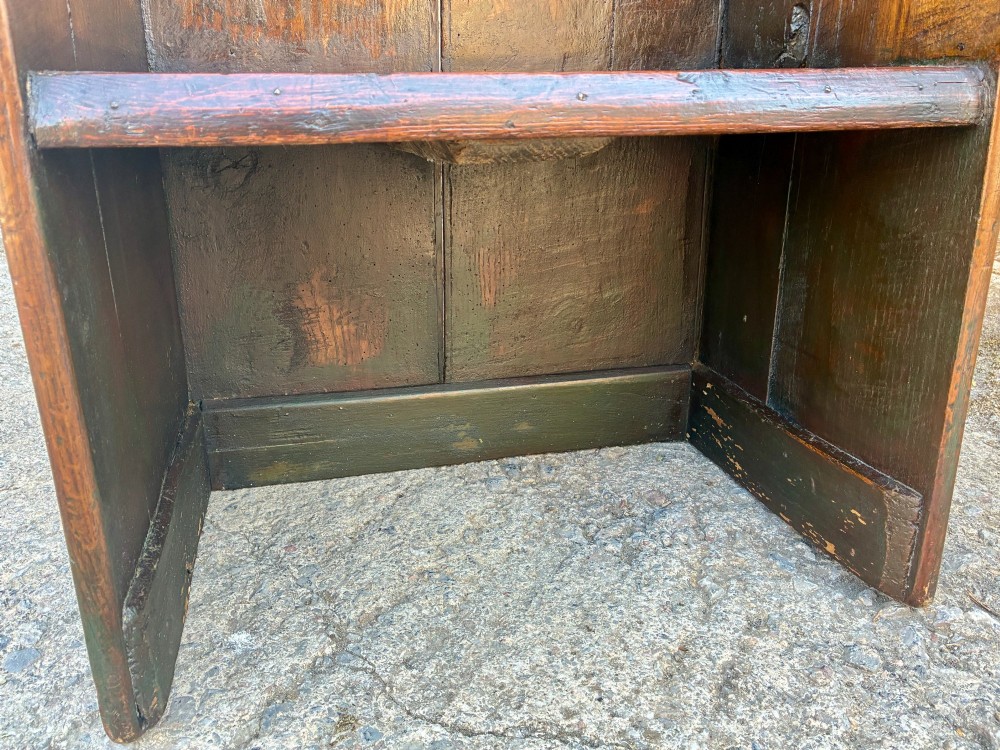 A dark oak primitive lambing chair featuring high winged sides, a tall two-panel back, a solid timber seat, and an enclosed box base. View XIV