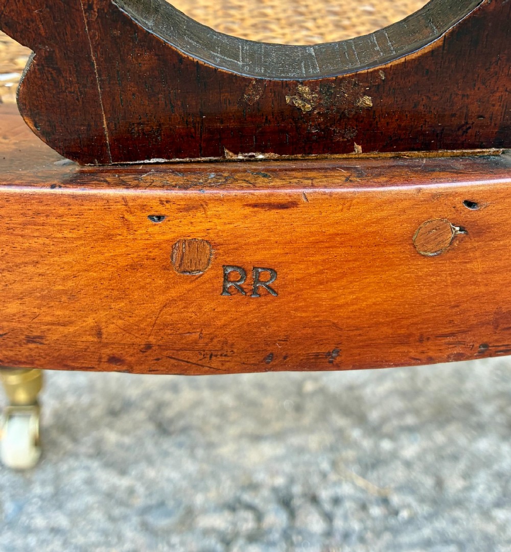 A Victorian mahogany desk chair featuring a curved top rail, pierced decorative splats, fabric-wrapped armrests, a woven cane seat, and turned legs with brass castors. View VII