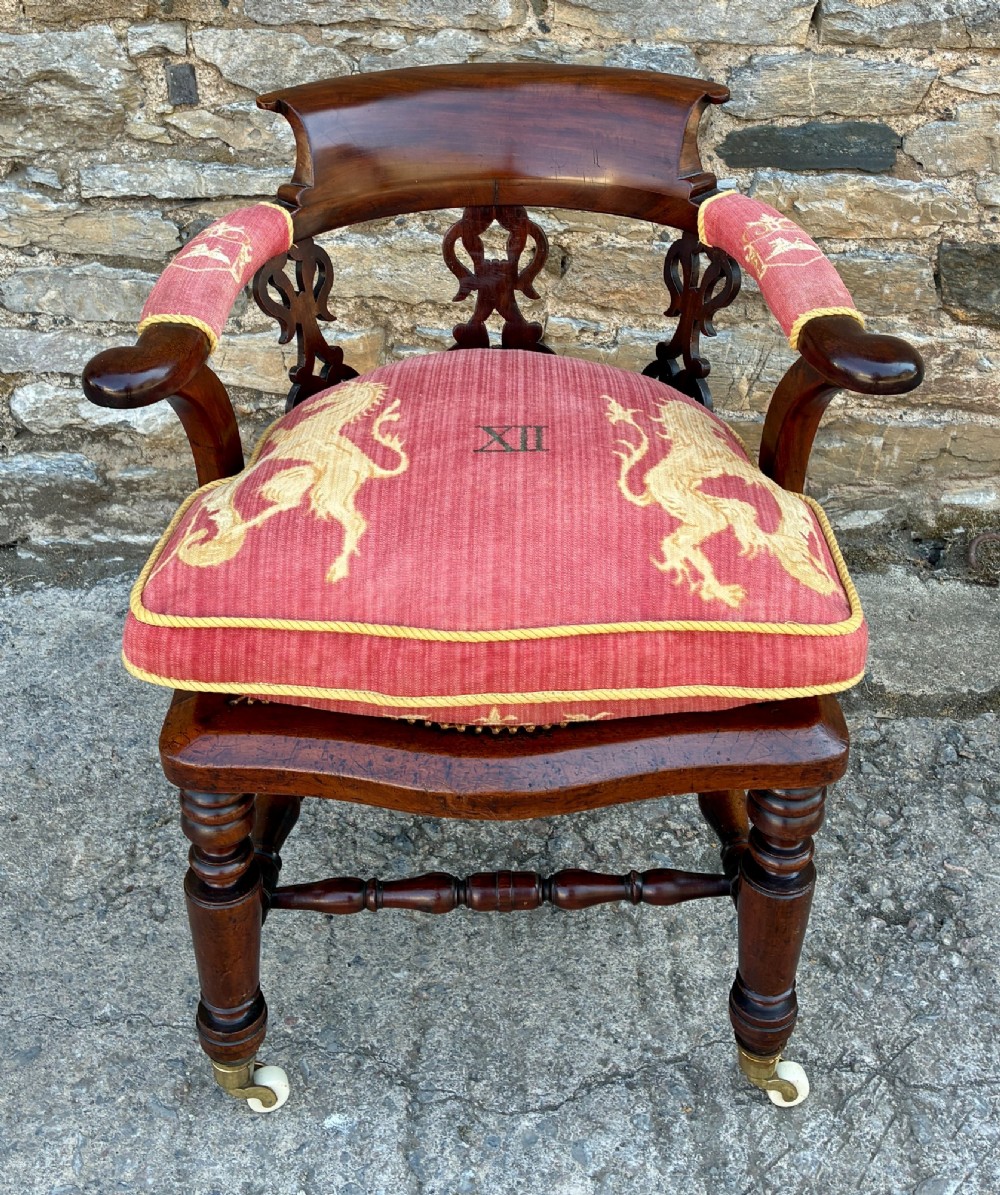 A Victorian mahogany desk chair featuring a curved top rail, pierced decorative splats, fabric-wrapped armrests, a woven cane seat, and turned legs with brass castors. View XIII