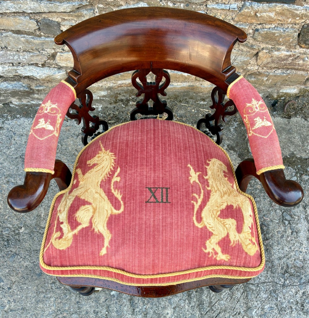 A Victorian mahogany desk chair featuring a curved top rail, pierced decorative splats, fabric-wrapped armrests, a woven cane seat, and turned legs with brass castors. View XIV