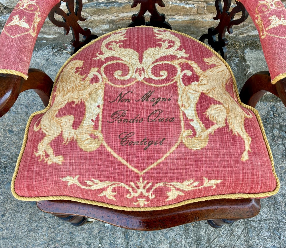 A Victorian mahogany desk chair featuring a curved top rail, pierced decorative splats, fabric-wrapped armrests, a woven cane seat, and turned legs with brass castors. View XV