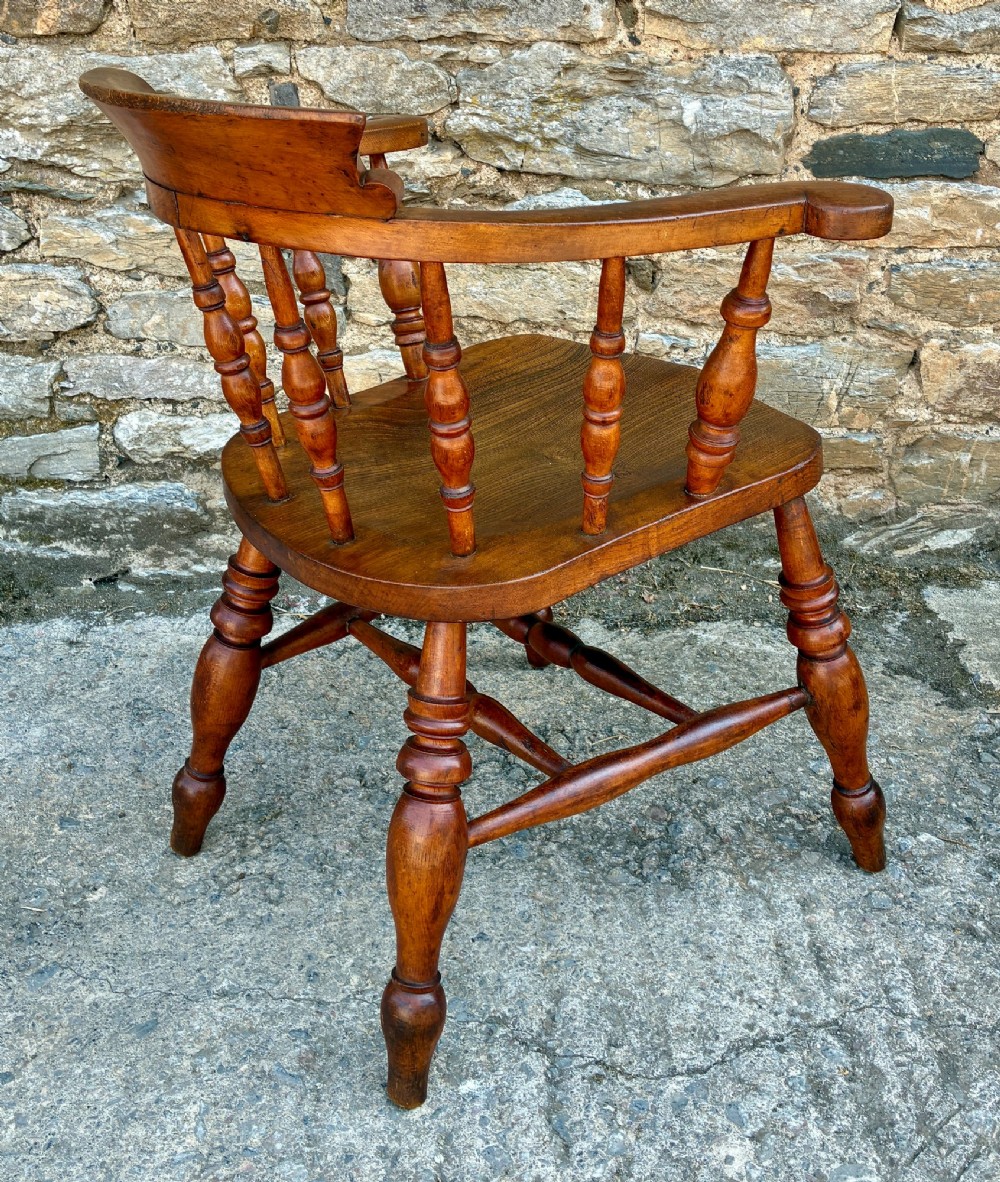 An antique wooden captains chair crafted from elm with turned spindles, a curved top rail, a contoured saddle seat, and turned legs. View VIII