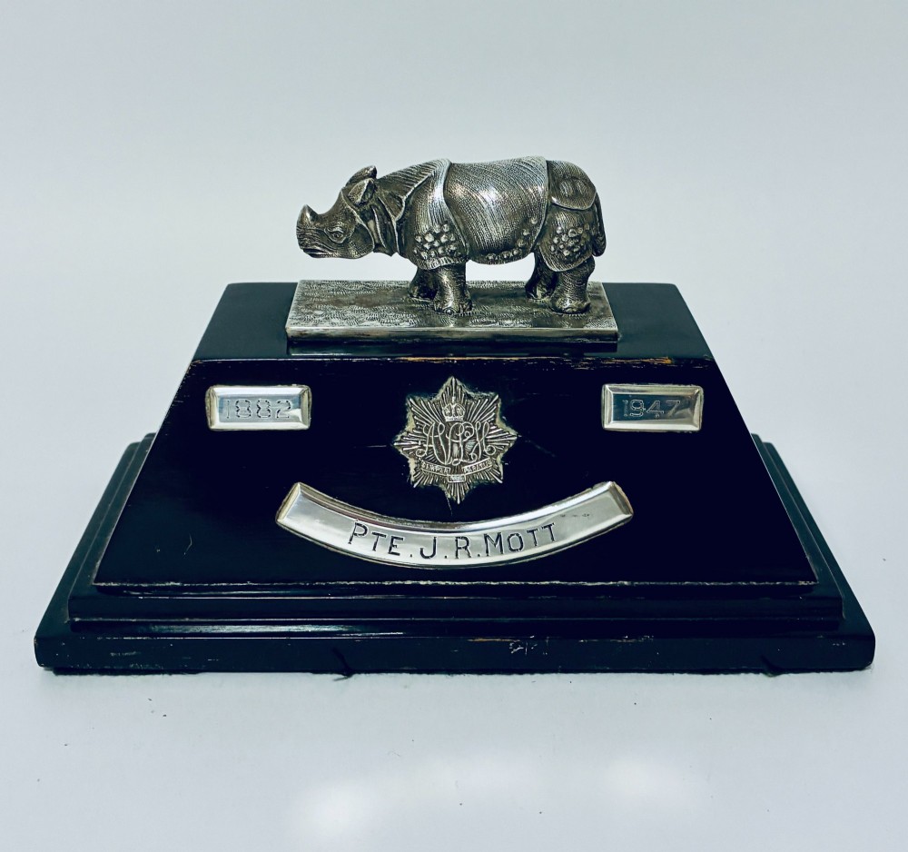An antique silver presentation trophy featuring a detailed Indian rhinoceros figurine mounted atop a stepped ebonised wooden plinth with silver plaques.
