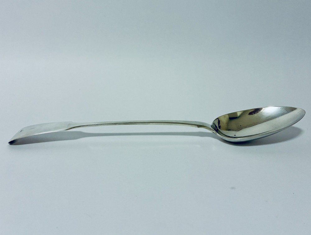 A Georgian sterling silver serving spoon featuring a polished oval bowl and a classic fiddle pattern handle resting against a plain light background. View III