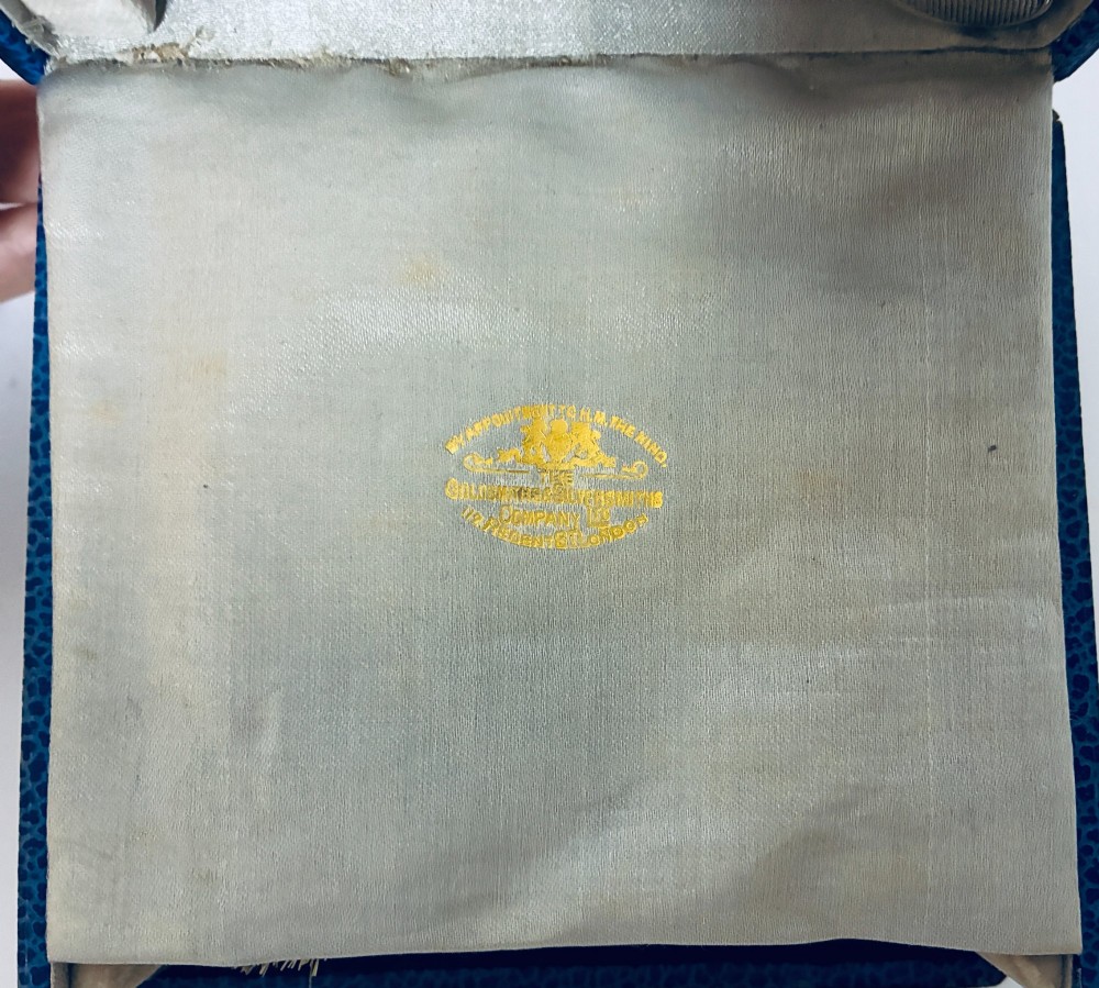 An open blue fitted presentation case displaying two silver-mounted brushes with light-coloured natural bristles against a grey velvet interior. View III