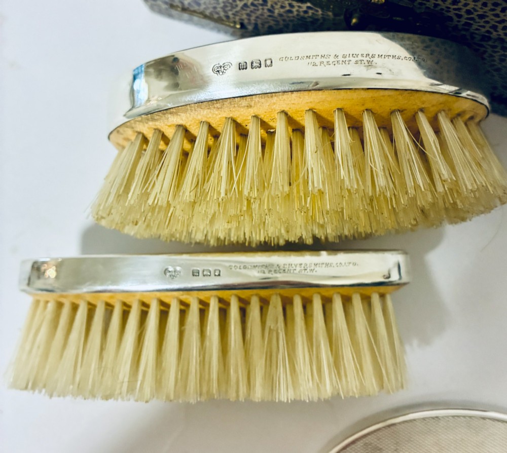 An open blue fitted presentation case displaying two silver-mounted brushes with light-coloured natural bristles against a grey velvet interior. View VIII
