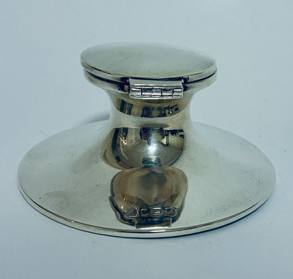 A polished silver capstan inkwell featuring a broad circular base, a tapered central waist, and a hinged flat lid. View III