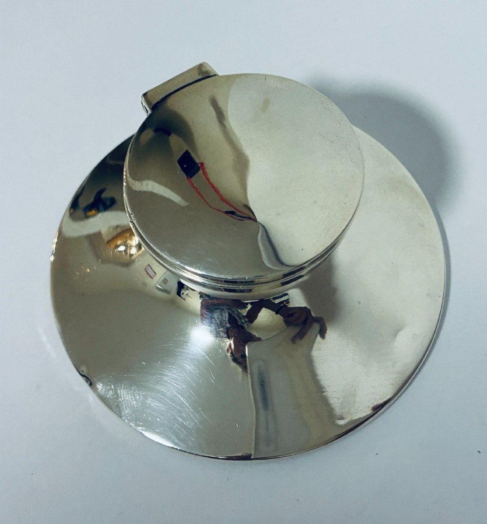 A polished silver capstan inkwell featuring a broad circular base, a tapered central waist, and a hinged flat lid. View VI