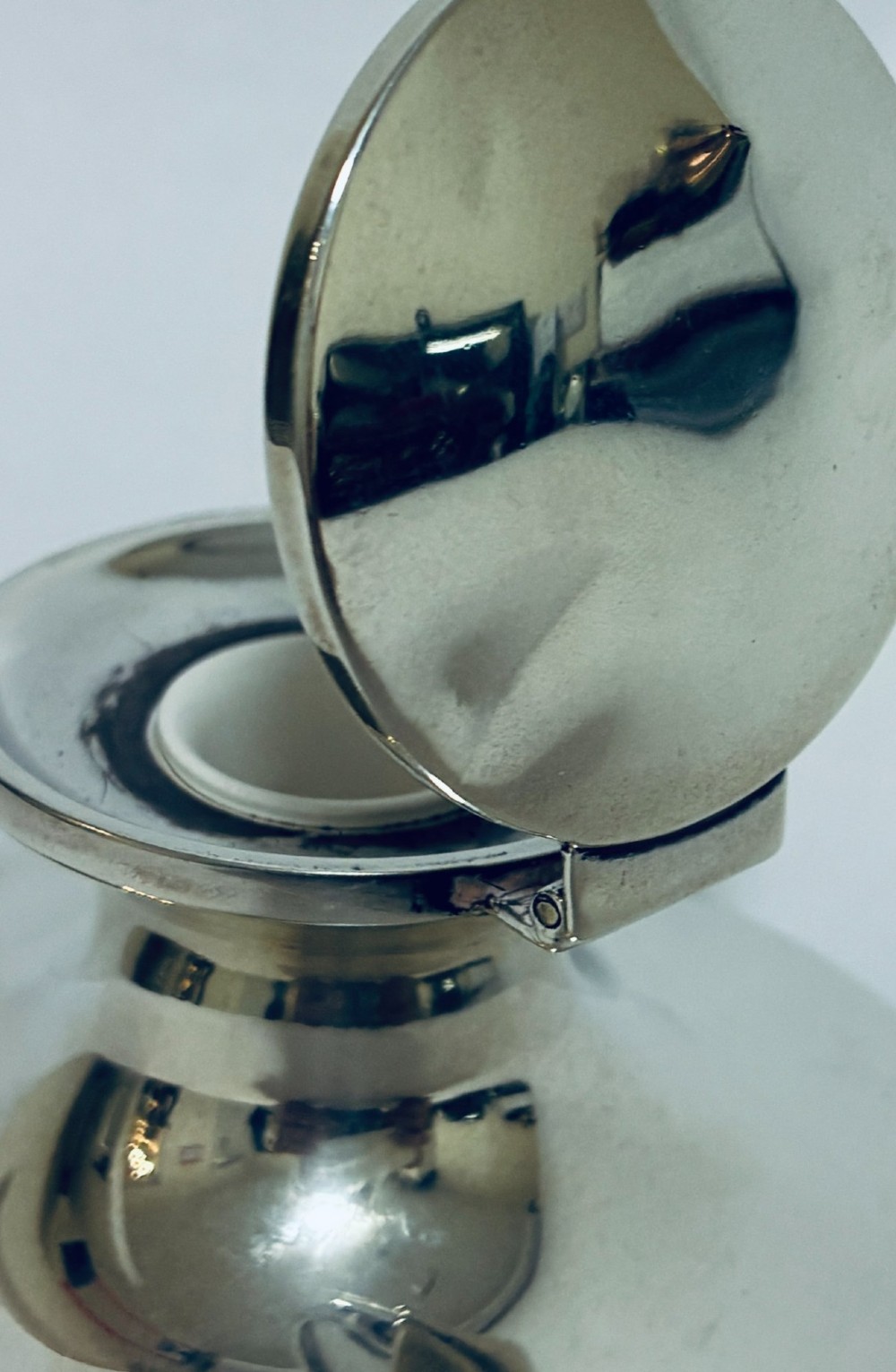 A polished silver capstan inkwell featuring a broad circular base, a tapered central waist, and a hinged flat lid. View VII