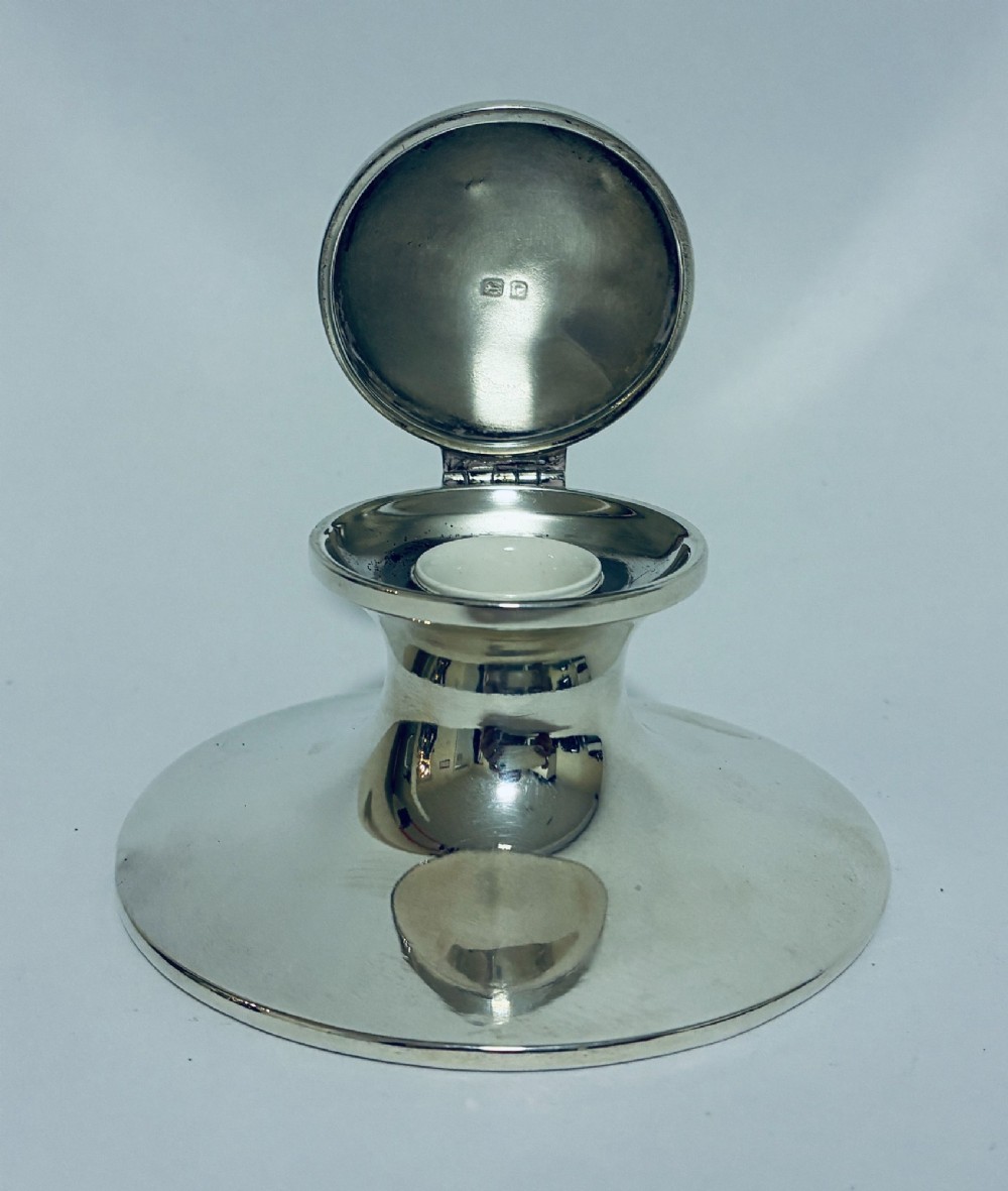 A polished silver capstan inkwell featuring a broad circular base, a tapered central waist, and a hinged flat lid. View VIII